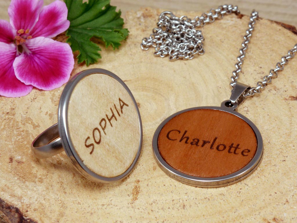 Conjunto de joyería personalizado de madera y acero, incluyendo un colgante y un anillo grabados con un nombre de mujer. Diseño elegante y moderno que combina la calidez de la madera con la durabilidad del acero, perfecto para un regalo único y significativo.