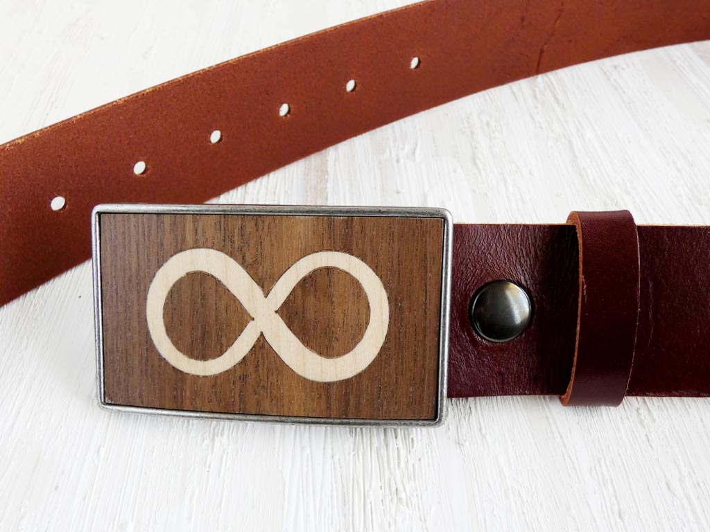 Hebilla de cinturón artesanal con el símbolo del infinito, creada mediante marquetería que combina madera natural de nogal y sicomoro. Este diseño elegante y significativo simboliza la continuidad y conexión, perfecto para quienes aprecian accesorios únicos y con profundo simbolismo.