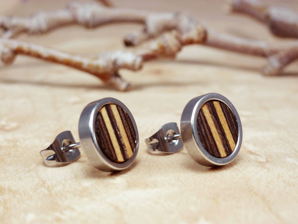 Pendientes redondos y pequeños hechos a mano, combinando madera y acero, con un diseño lineal distintivo que utiliza dos tipos de madera natural. Joyería ecológica y artesanal perfecta para un estilo sostenible y moderno.