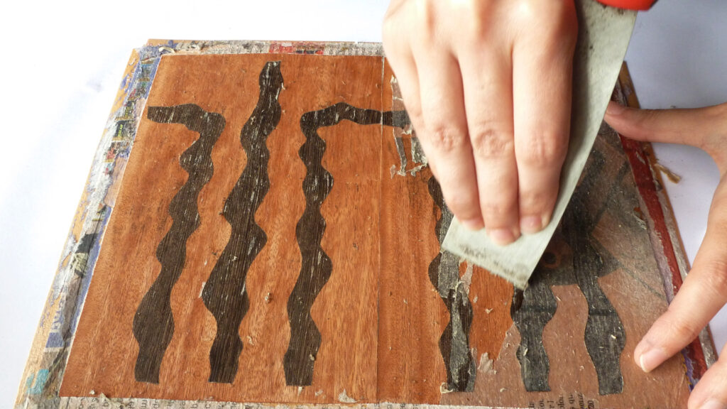 Removing the paper from a marquetry piece using water and a spatula.