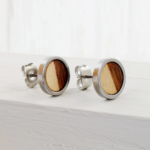 Close-up of handmade earrings with walnut and sycamore wood and stainless steel base