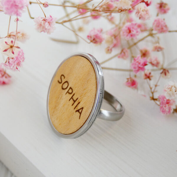 Engraved wooden ring with name in natural wood and steel band.