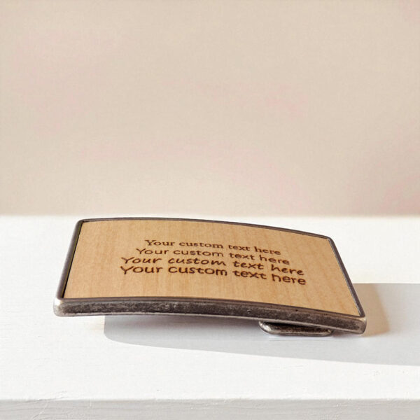 Personalized men's buckle with custom text on wood and metal base.
