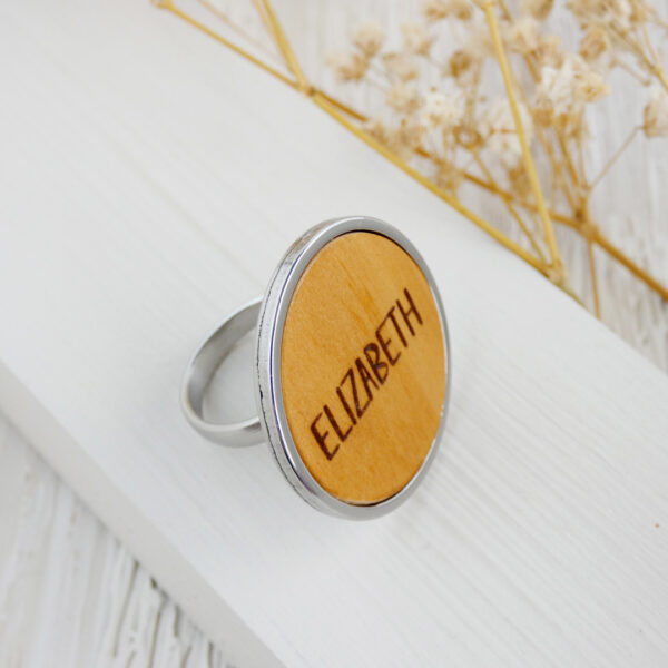 Ring with name engraved in natural wood and mounted on a stainless steel adjustable band.