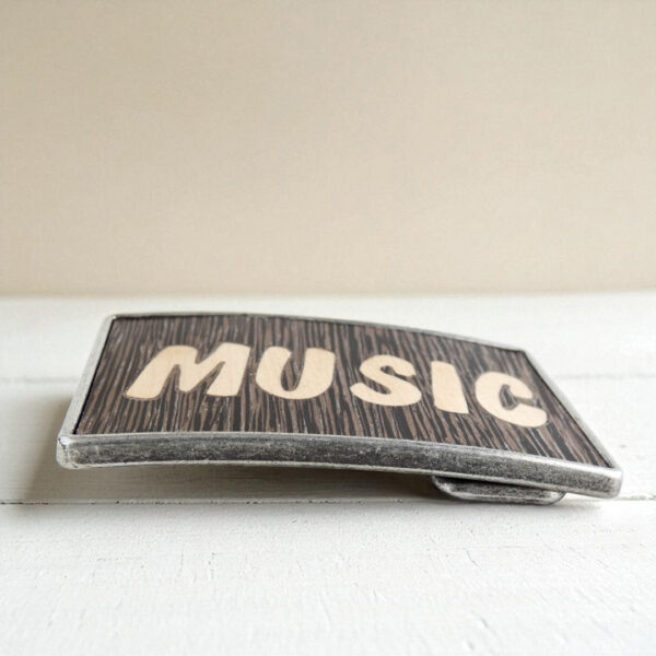 Belt buckle with wood inlay spelling MUSIC on a curved metal base
