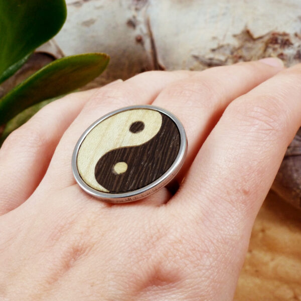 Handmade yin yang ring in wood and steel, shown worn on a hand